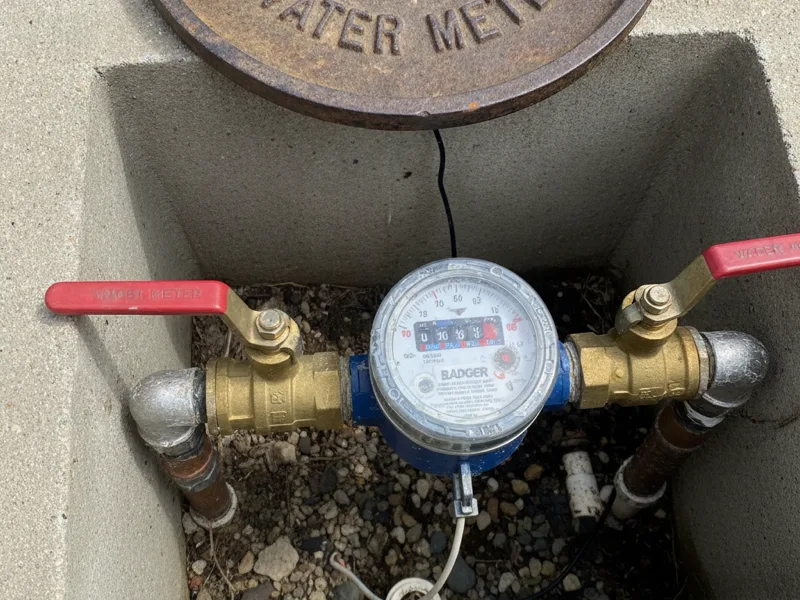 Close-up of a residential water meter and main shutoff valve